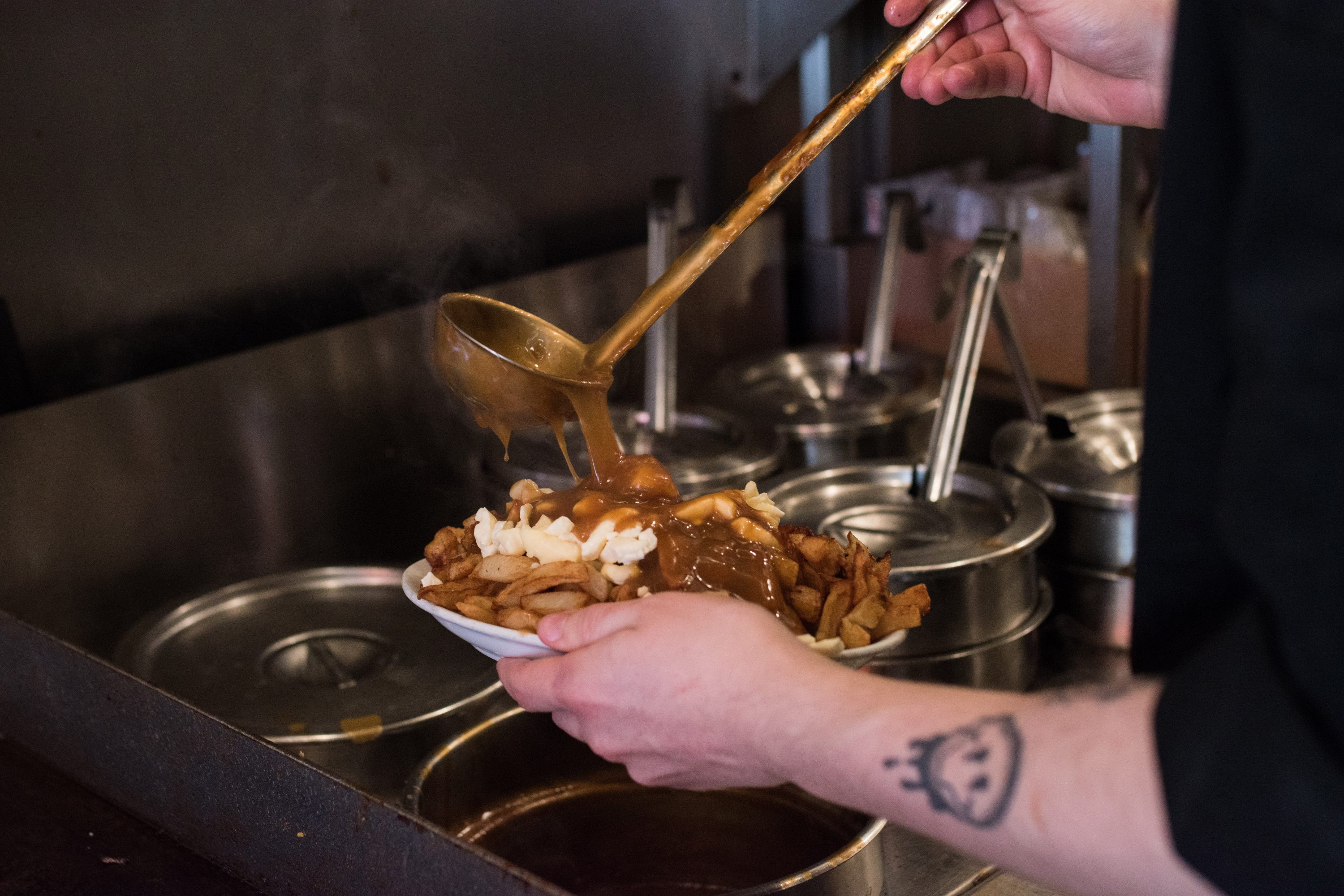 A chef adds gravy to a poutine