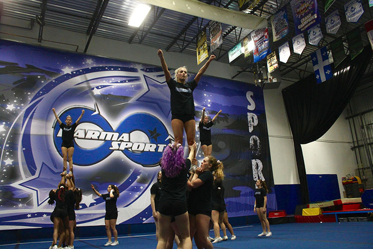 Three cheerleaders are lifted and supported by their bases