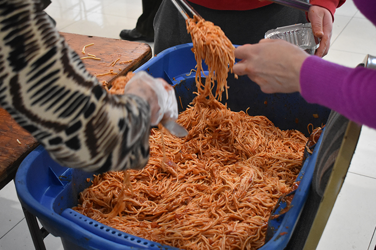 A large bin full of cooked spaghetti.