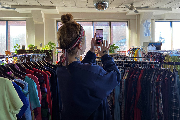A woman films a TikTok video in a thrift store