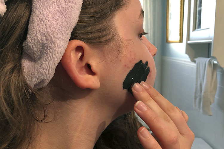 A woman applying a skincare mask