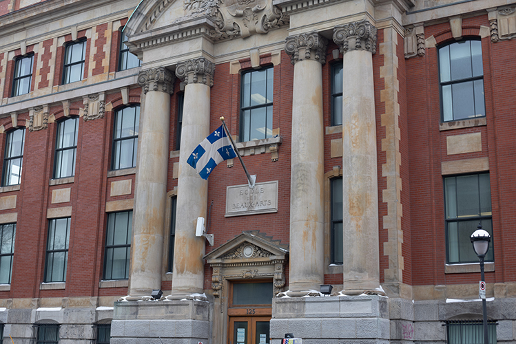 The outside of the OQLF building. The Quebec flag hangs above the entrance.