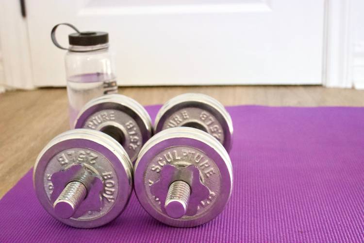 Weights and a water bottle on a yoga mat