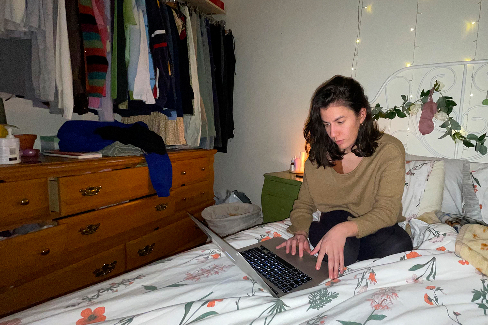 Women sitting on her bed while on the computer.