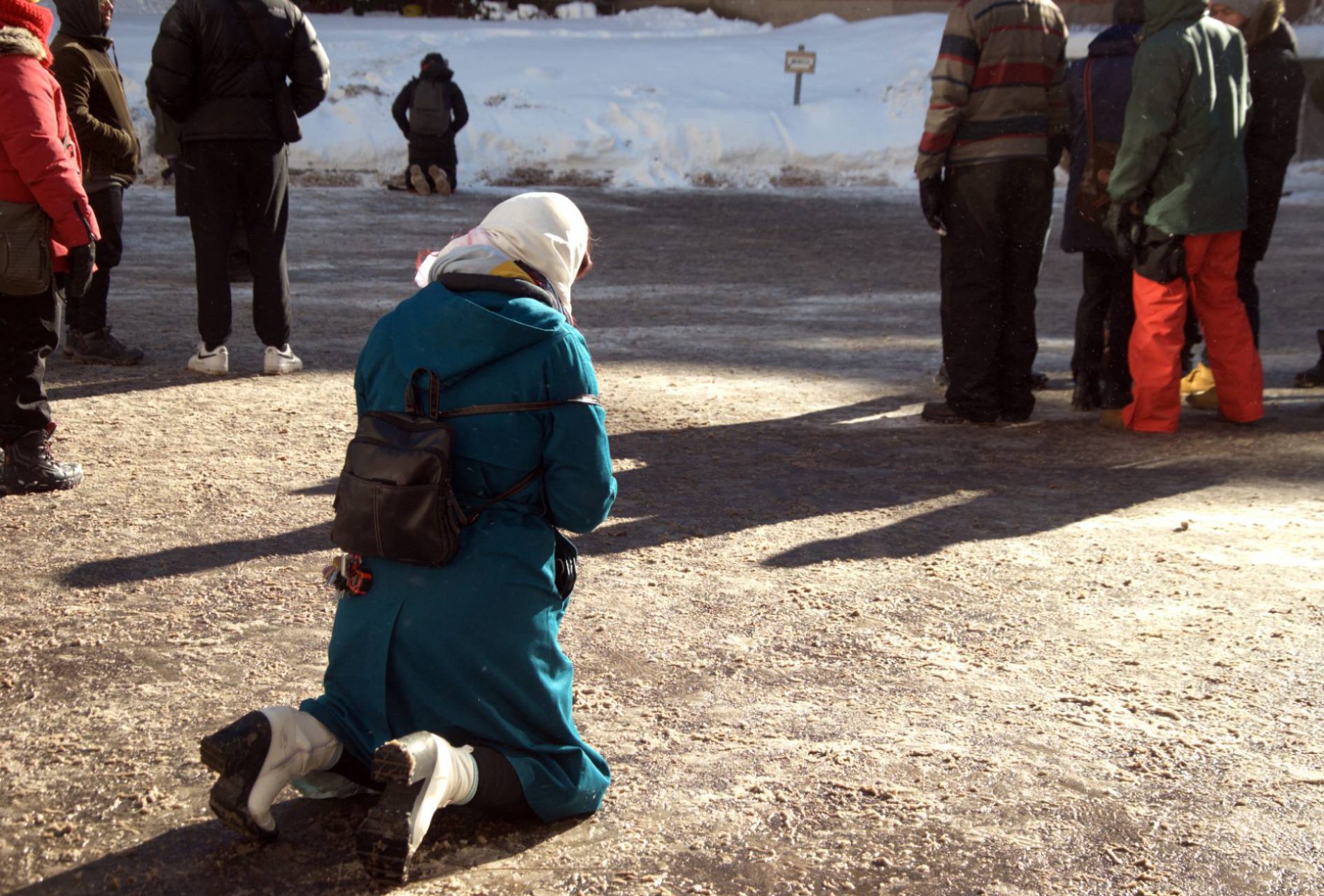 worshipper kneeling down onto the icy ground of the parking lot behind the Montreal cathedral during the mass