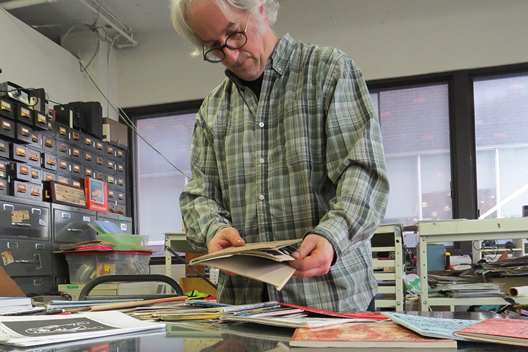 Louis Rastelli, director of Arcmtl looking at zines in the office.
