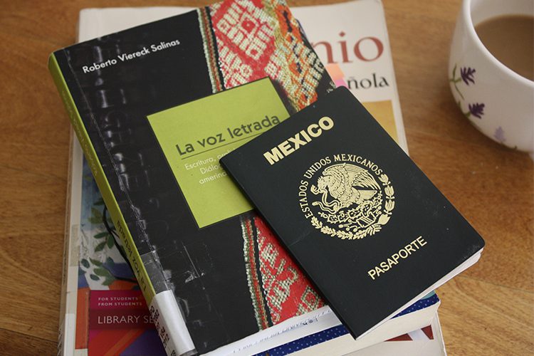 Mexican passport on stack of books in Spanish