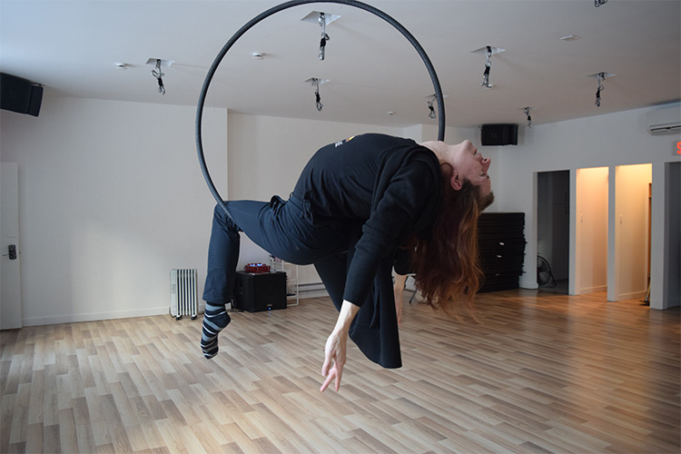 A woman hangs from a hula hoop that is secured to the ceiling.