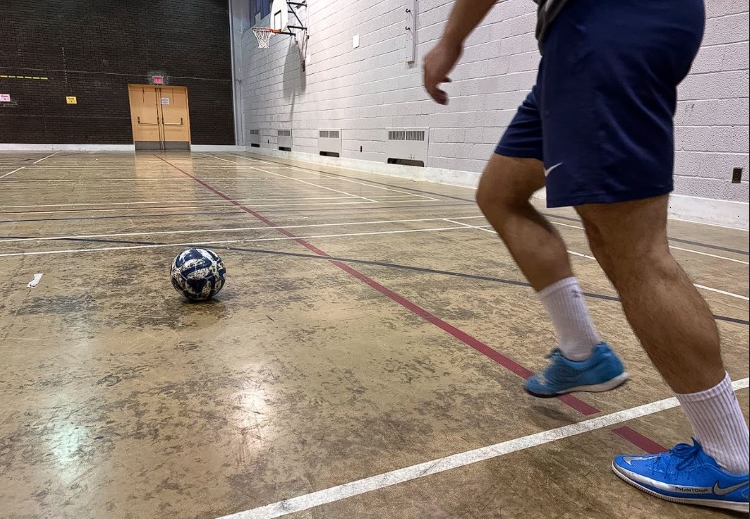 A soccer player kicking a ball indoors
