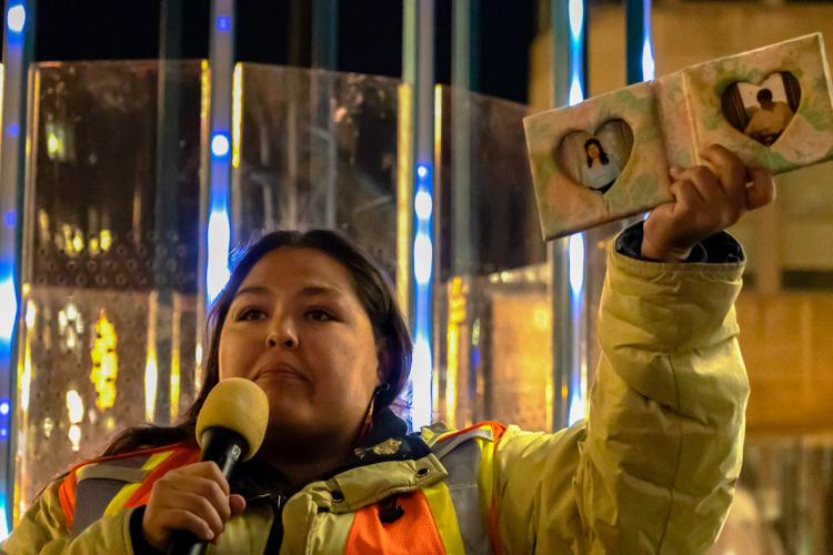 Janis Qavanauq-Bibeau holds up a picture of her mother towards the crowd of protesters.