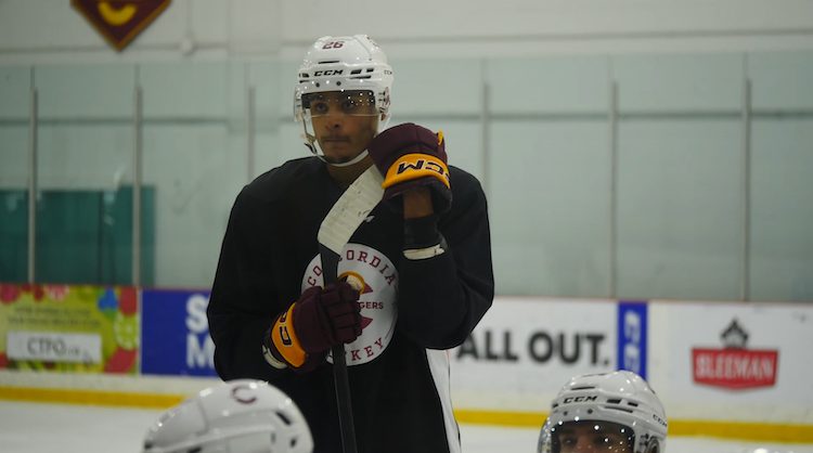 Hockey Player Isiah Campbell listening to his coach during practice