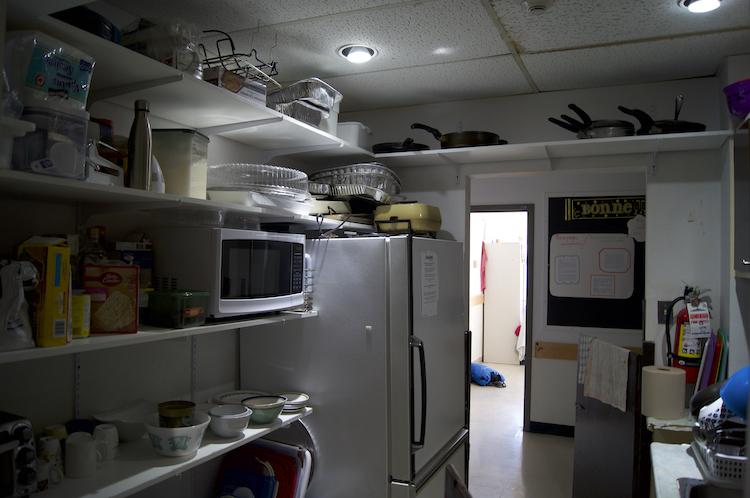 A communal kitchen full of pots and pans, a microwave and a fridge