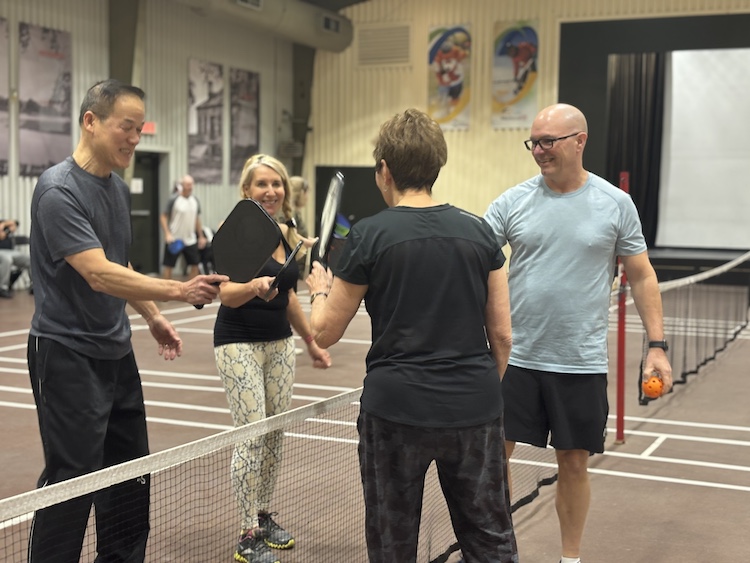 Group of pickleball players touching paddles at the end of the game.