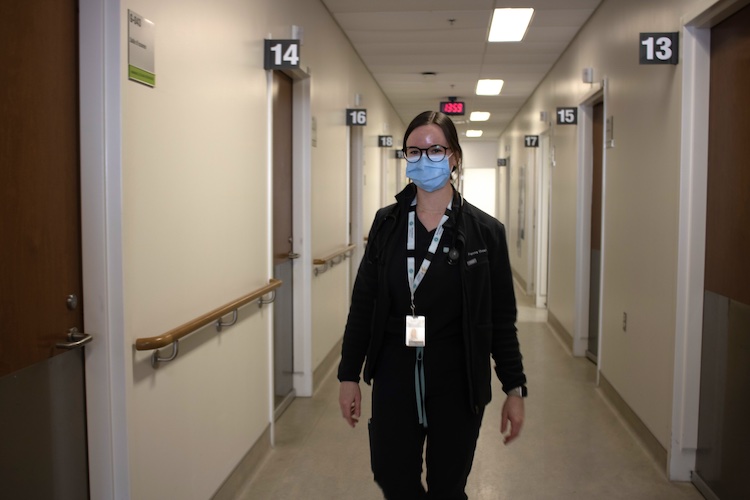 Front view of a nurse walking toward the camera in a hospital hallway.