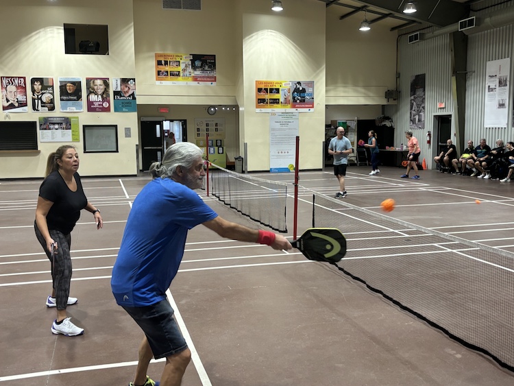 Man hitting ball while partner waits to the side