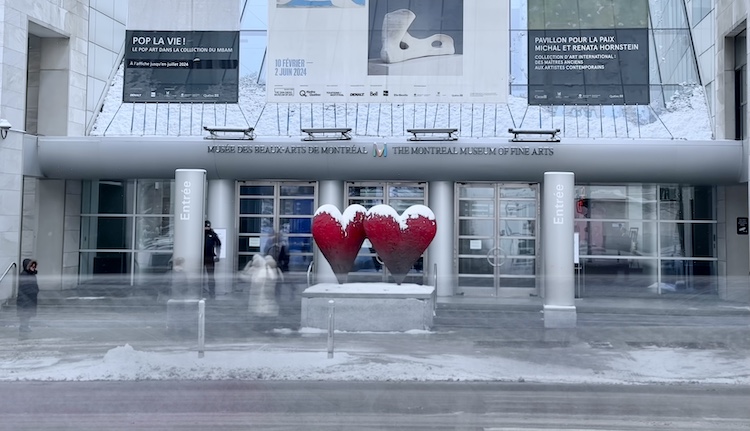 Two hearts are pictured outside the Montreal Museum of Fine arts as cars drive by.